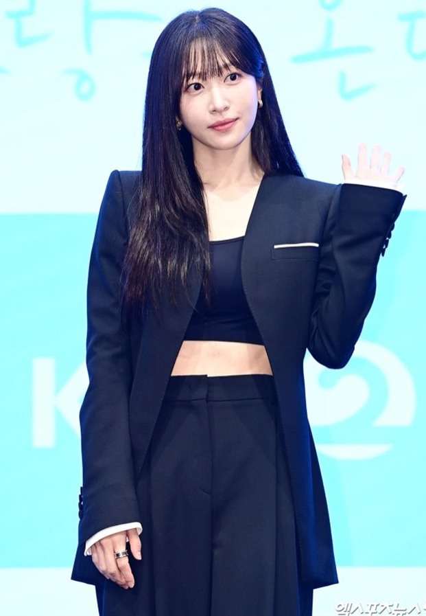 ภาพครึ่งตัว Hani EXID ในชุดสูทสีดำยกมือทักทาย